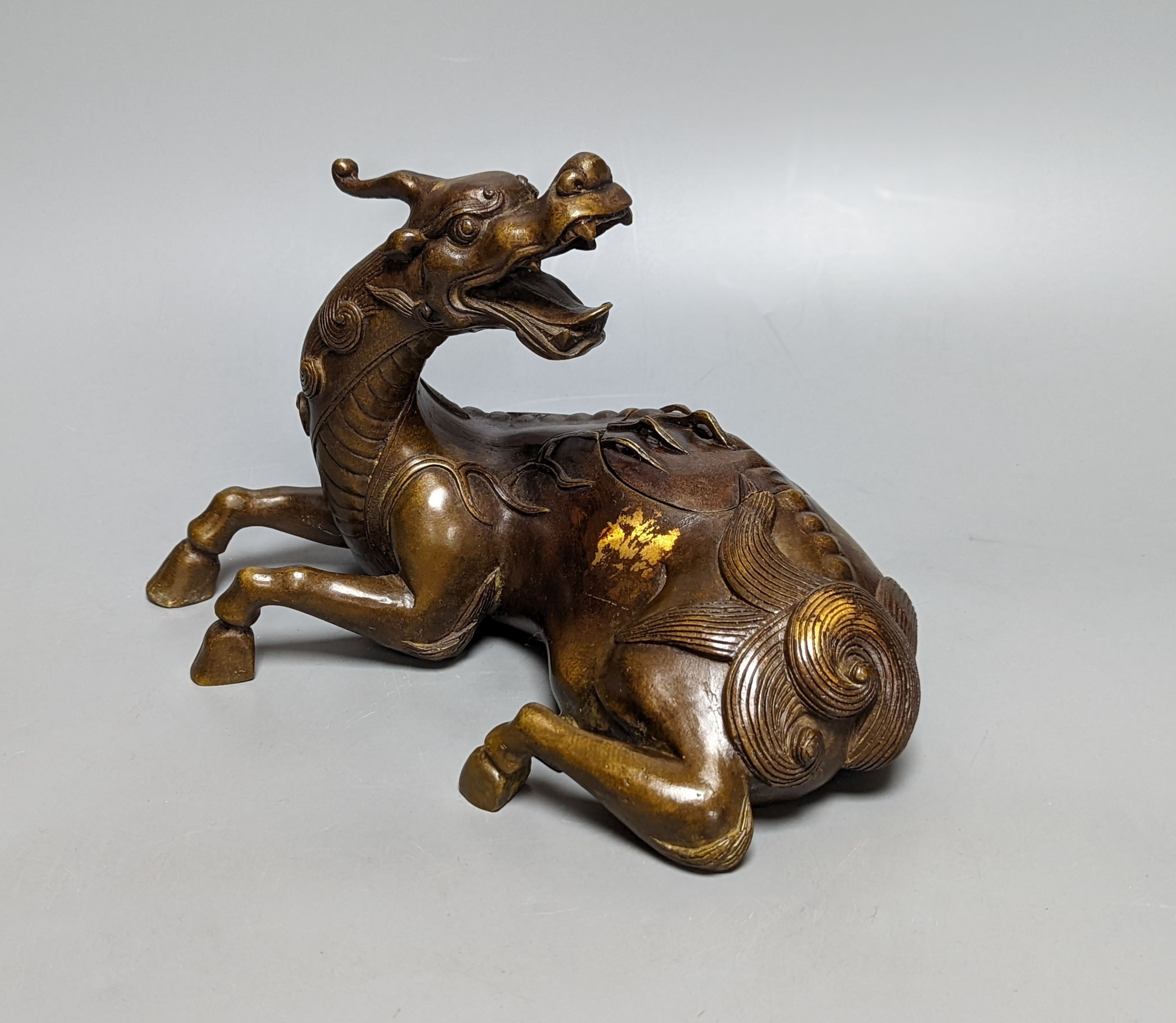 A Chinese parcel-gilt bronze incense burner and cover, modelled as a recumbent qilin, Qing dynasty, 19th century, 25 cms wide.